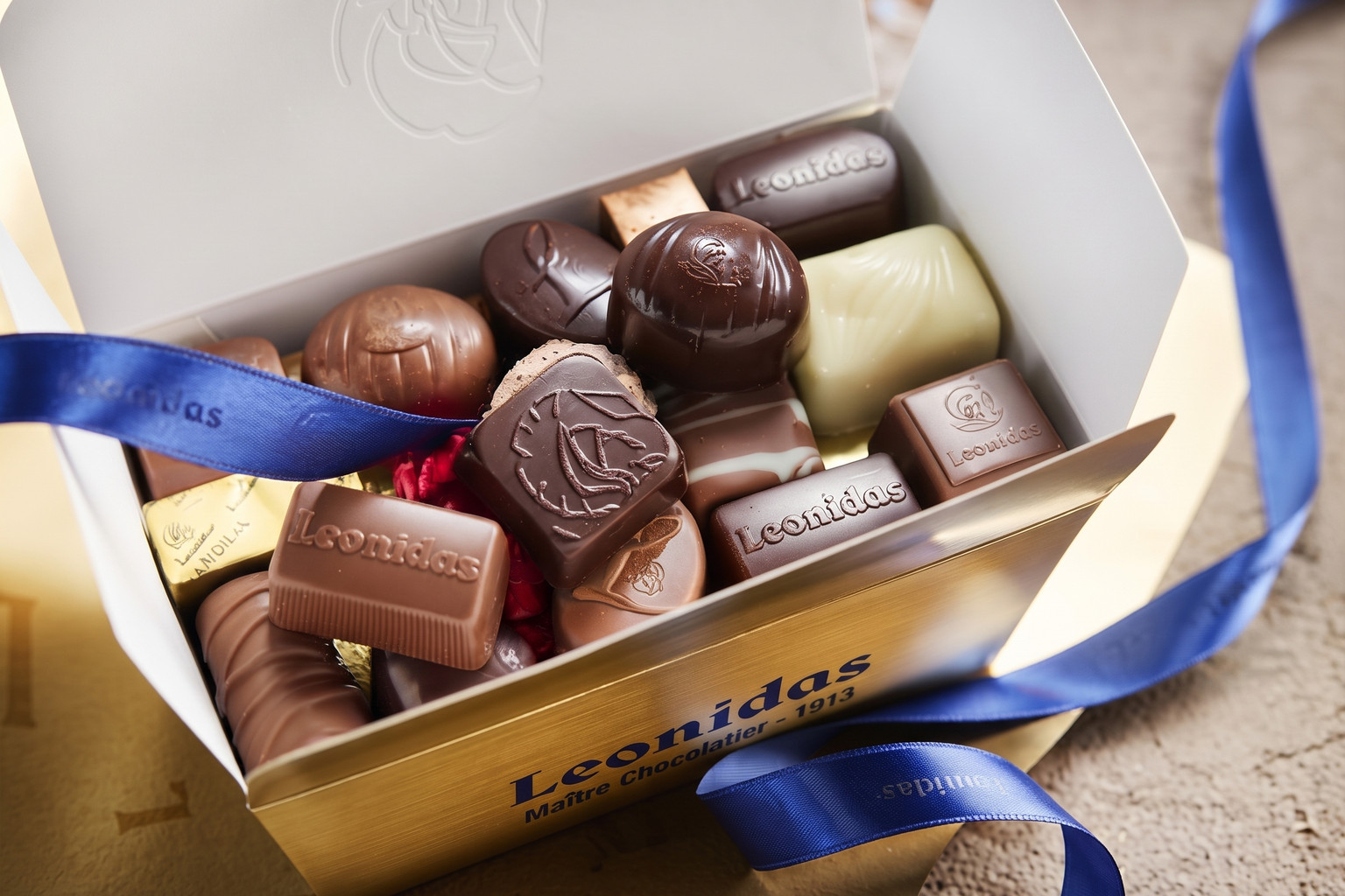 Gros plan sur un coffret doré ouvert rempli de bonbons chocolatés